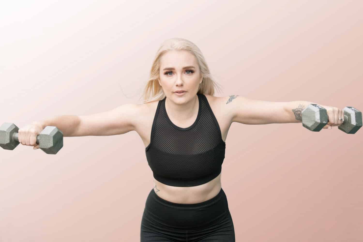 Personal Branding blonde fitness trainer extended arms with weights blush gradient background