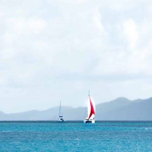 layers of blue ocean with red and white sailboat on BVI island background 2