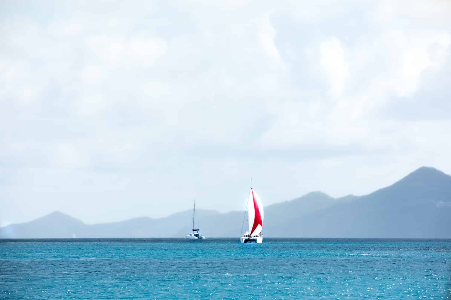layers of blue ocean with red and white sailboat on BVI island background 2